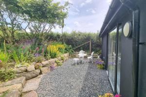 a patio with a table and chairs in a garden at Hallegan Annexe with Private Garden and Woodland in Camborne