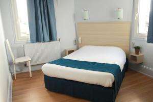 a bedroom with a bed and a chair at Hôtel De La Cathédrale in Reims