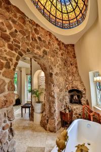 a bathroom with a stone wall and a window and a tub at MacLeod House Guest Cottage in Kloof