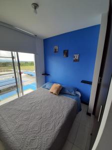 Dormitorio azul con cama y pared azul en Aptos y piscina cerca al Parque del café, en Armenia