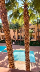 a pair of palm trees next to a swimming pool at Geweldig Appartement in Los Alcázares direct aan de Boulevard in Los Alcázares