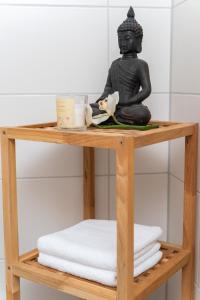 une statue noire assise sur une étagère en bois dans une salle de bains dans l'établissement Art City Studio Kassel, à Cassel