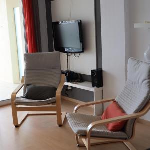 sala de estar con 2 sillas y TV en Appartement Port Gran Oceanic 2, en Roses