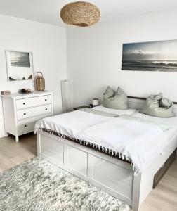 a white bedroom with a large bed and a dresser at Ferienwohnung Lauer in Ellerstadt