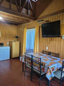 Zimmer mit einem Tisch und einem Flachbild-TV in der Unterkunft Cabañas rio ñilque in Ñilque