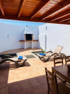 un patio con sillas, mesa y chimenea en Vivienda Vacacional Naia, en La Asomada