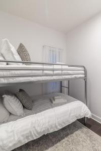 a bunk bed with white sheets and pillows on it at Parc Avenue Residences Mile End in Montréal