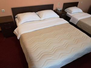 a hotel room with two beds with white sheets at Hotel Elegance in Belgrade