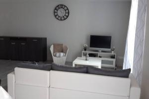sala de estar con sofá blanco y reloj en la pared en La maison d'Emmanon, en Saint-Saturnin-du-Bois