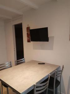 mesa con sillas y TV en la pared en Arbousiers A44, en Léon
