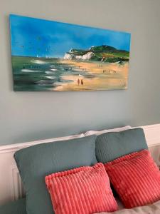 a painting of a beach and two pillows on a couch at Sainte-Cécile La Cabine Chic 4 personnes in Camiers