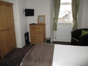 a bedroom with a bed and a dresser and a television at Hillside Bed & Breakfast in Kendal