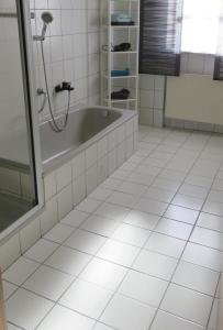 a bathroom with a tub and a white tiled floor at Ferienwohnung Fernblick Breitenberg in Breitenberg