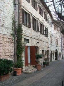 un viejo edificio de ladrillo con una puerta roja en una calle en La piazzetta delle erbe, en Asís