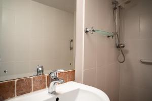 een badkamer met een wastafel en een douche met een spiegel bij Winchelsea Lodge in Winchelsea