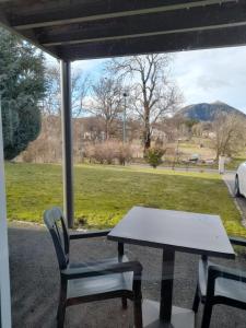 una mesa y sillas sentadas en un porche con vistas a un campo en A 5 mns du Puy de Dôme avec Vue imprenable Studio rez de jardin 24m2 neuf à Laschamps en Saint-Genès-Champanelle