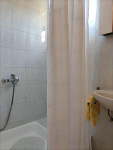 a bathroom with a shower curtain and a sink at Kuća Carmen in Rab