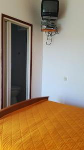 a bedroom with a bed with a tv on the wall at Kuća Carmen in Rab