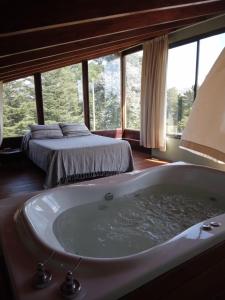 - une baignoire dans une chambre avec un lit dans l'établissement La Azotea cabañas & suites, à La Cumbrecita