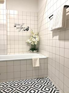 a bathroom with a tub and a vase of flowers at Apartman Favorita in Vienna