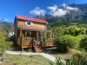a log cabin with a deck and mountains in the background at La CAFRINE in Cilaos