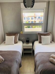 2 camas en una habitación con ventana y mesa en Résidence Saradon La Zenia Boulevard, en Los Dolses