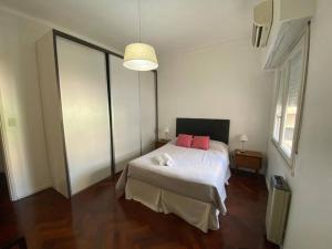 1 dormitorio con 1 cama con 2 almohadas rosas en Pacífico departamento en Palermo en Buenos Aires