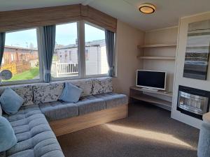 uma sala de estar com um sofá e uma televisão em Beachside caravan em Mablethorpe