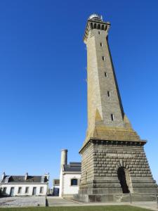 a tall brick lighthouse in front of a building at les volets bleus in Saint-Guénolé