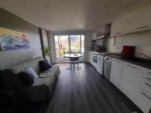 uma sala de estar com um sofá e uma cozinha com uma mesa em A 5 mns du Puy de Dôme avec Vue imprenable Studio rez de jardin 24m2 neuf à Laschamps em Saint-Genès-Champanelle