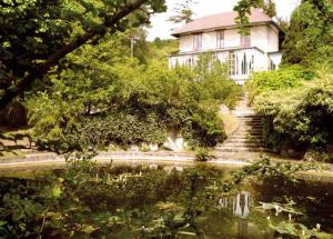una casa con un estanque frente a una casa en La Pluie de Roses, en Giverny