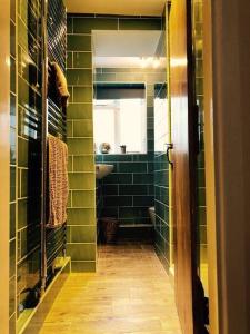 a green tiled bathroom with a sink and a mirror at The Farthings Cotswolds Holiday Cottage in Chipping Campden
