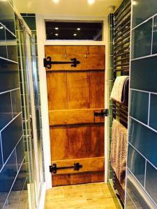 - Puerta de madera en el baño con ducha en The Farthings Cotswolds Holiday Cottage, en Chipping Campden
