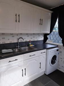 a kitchen with white cabinets and a sink and a dishwasher at Beach & Tonic beachside chalet in Humberston