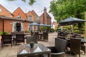 an outdoor patio with tables and chairs and umbrellas at The Bell by Innkeeper's Collection in Aston Clinton