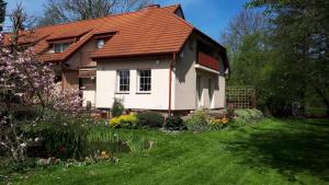 una casa con techo rojo y patio verde en Pokoje Gościnne POD KNOTEM, en Karwieńskie Błoto Drugie