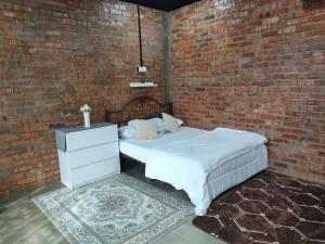 Studio Amani Permatang Pauh في Permatang Pauh: غرفة نوم بحائط من الطوب وسرير ابيض