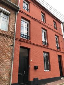 a red brick building with a black door and windows at Maison Gabriel Appartement BULLE in Abbeville