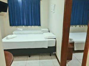 2 camas en una habitación pequeña con cortinas azules en Oceano Pousada - Buffet de café da manhã e serviço de quarto diário, en Bombinhas
