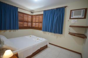 um quarto com uma cama com cortinas azuis em Oceano Pousada - Buffet de café da manhã e serviço de quarto diário em Bombinhas