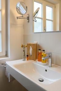 W łazience znajduje się biała umywalka i lustro. w obiekcie Adler Schiltach Boutique Hotel und Restaurant w mieście Schiltach