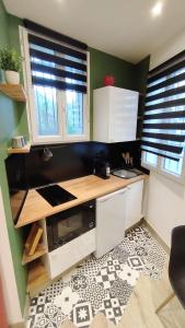 a small kitchen with a counter and two windows at Studio de charme climatisé Gare Riquier in Nice