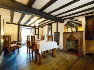 a dining room with a table and a fireplace at Laburnham Cottage in Stowmarket