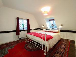 a bedroom with a bed and a red rug at Laburnham Cottage in Stowmarket