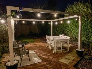 a patio with a table and chairs under a pergola at night at Laburnham Cottage in Stowmarket