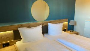 a bedroom with a bed with white pillows and a mirror at Hotel Kiose - Ferienwohnungen in Wenningstedt