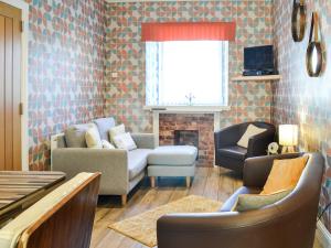 a living room with a couch and chairs and a fireplace at Park View Cottage in Stranraer