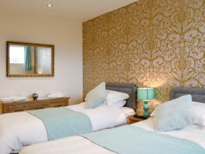 two beds in a room with a mirror on the wall at Park View Cottage in Stranraer