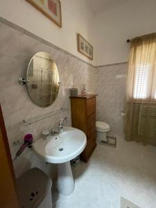 een badkamer met een wastafel, een spiegel en een toilet bij B&B Casa Mimì in San Ferdinando di Puglia