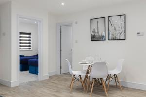 a dining room with a table and white chairs at Star London Vivian Avenue 2-Bed Haven in The Hyde